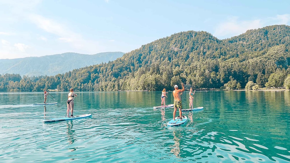 People paddleboarding on a calm lake surrounded by forested hills. 4