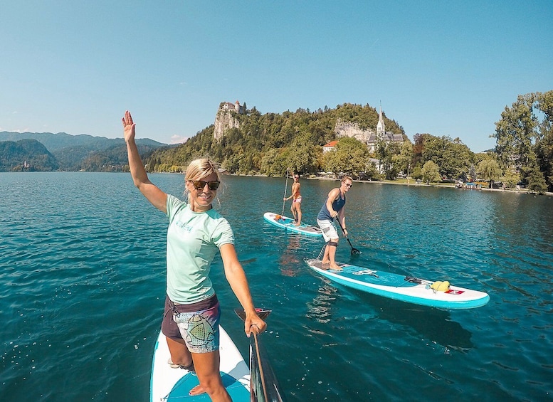 Three people paddleboarding on a calm lake with a castle on a hill in the background. 3