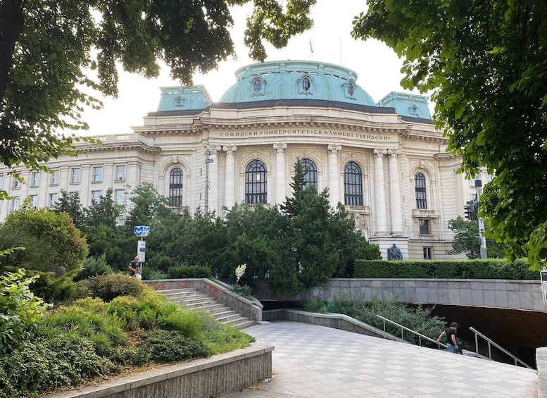 A large, historic building with a dome and columns, surrounded by lush greenery and a staircase leading up to it. 5