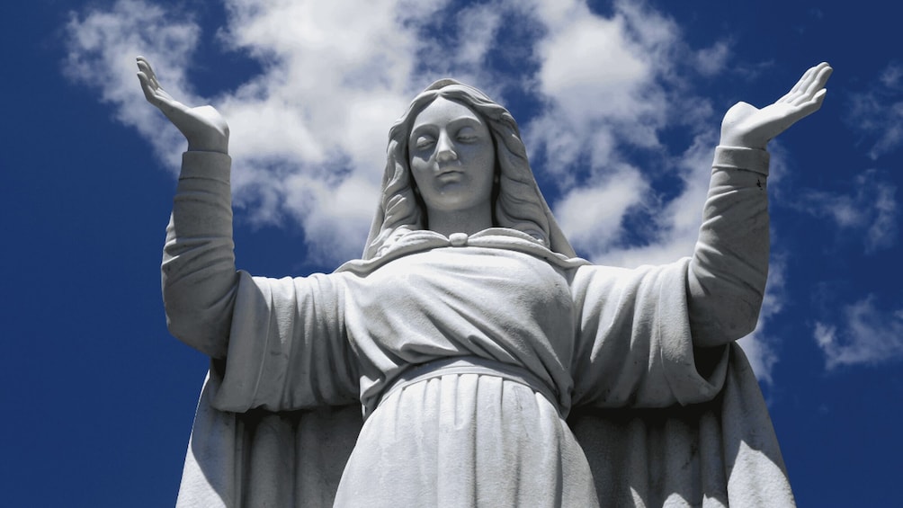 A statue with outstretched arms against a blue sky with clouds. 5