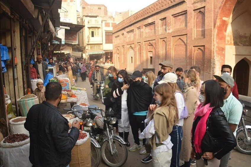 Een drukke marktstraat met mensen die kraampjes bekijken en een historisch gebouw op de achtergrond. 4