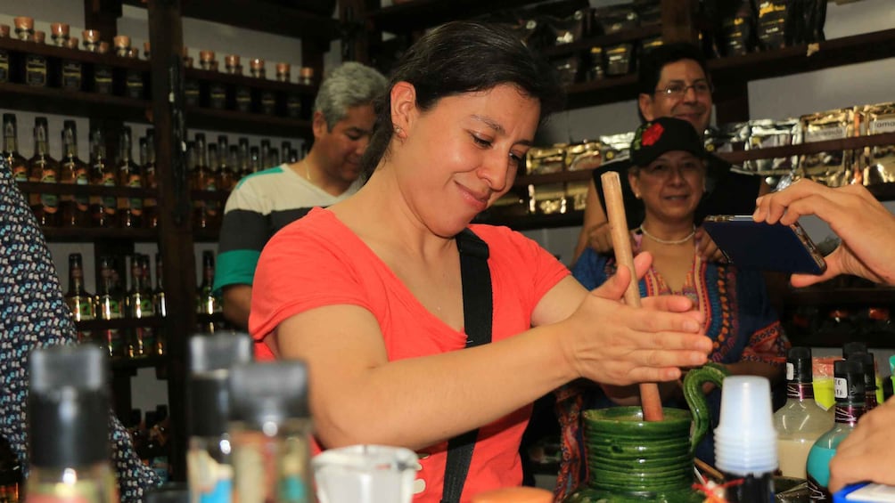 A person mixing drinks at a bar with shelves of bottles in the background. 5