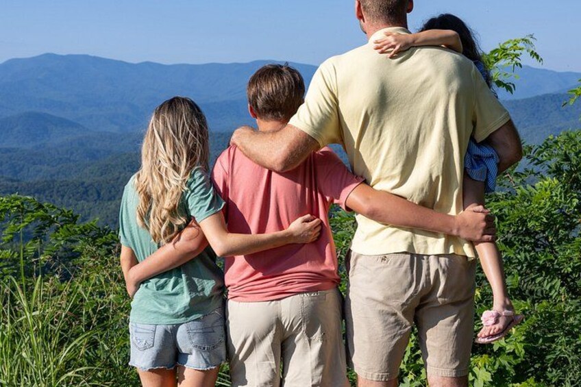 Une famille de quatre personnes, debout côte à côte, contemplant un paysage montagneux. 5