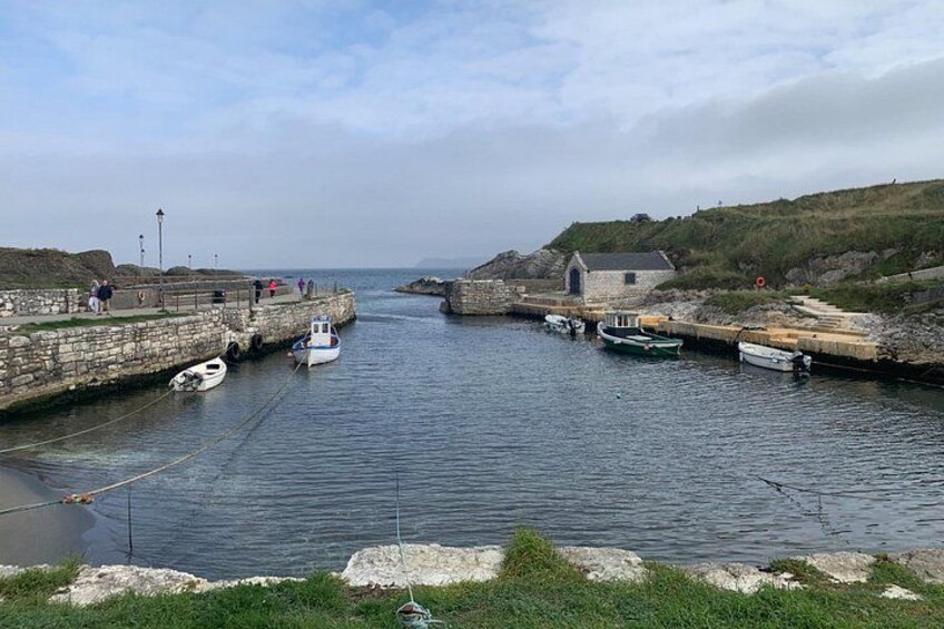 A harbor with boats docked, a stone pier, and a small building. 1