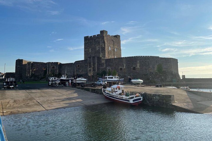 Un castillo con un foso, barcos amarrados en un muelle y un cielo despejado. 2