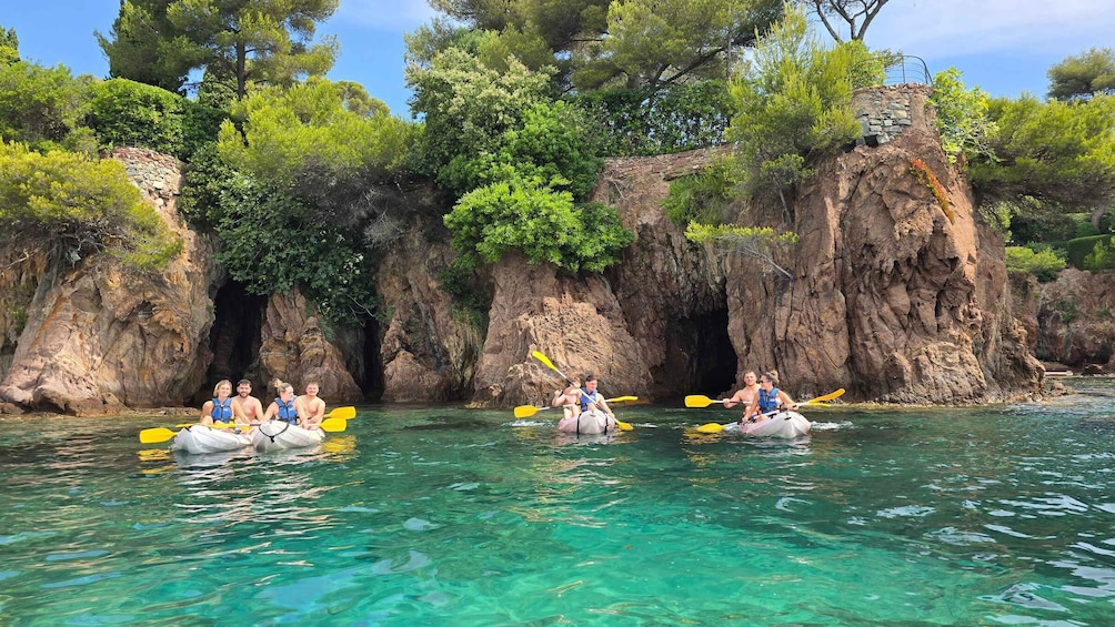 People kayaking on a clear turquoise river surrounded by rocky cliffs and lush greenery. 1