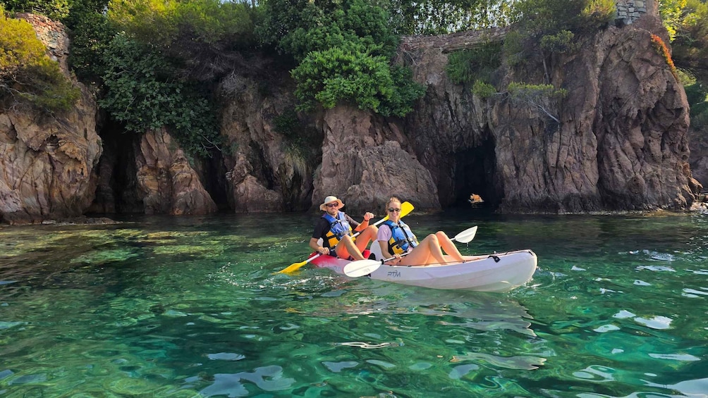 Two people kayaking in clear water with rocky cliffs in the background. 5