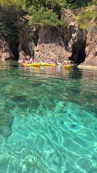 People kayaking in clear water with rocky cliffs in the background. 3
