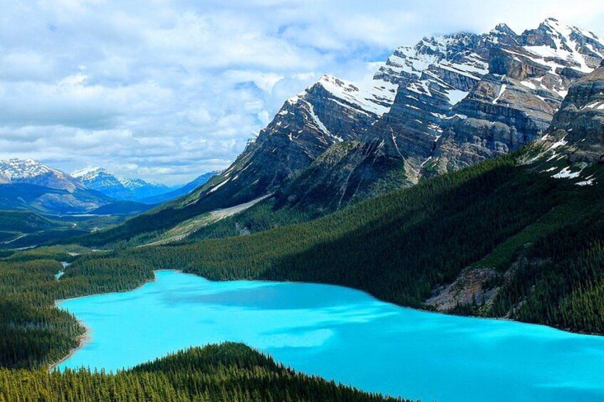 A turquoise lake surrounded by dense forests and snow-capped mountains. 3