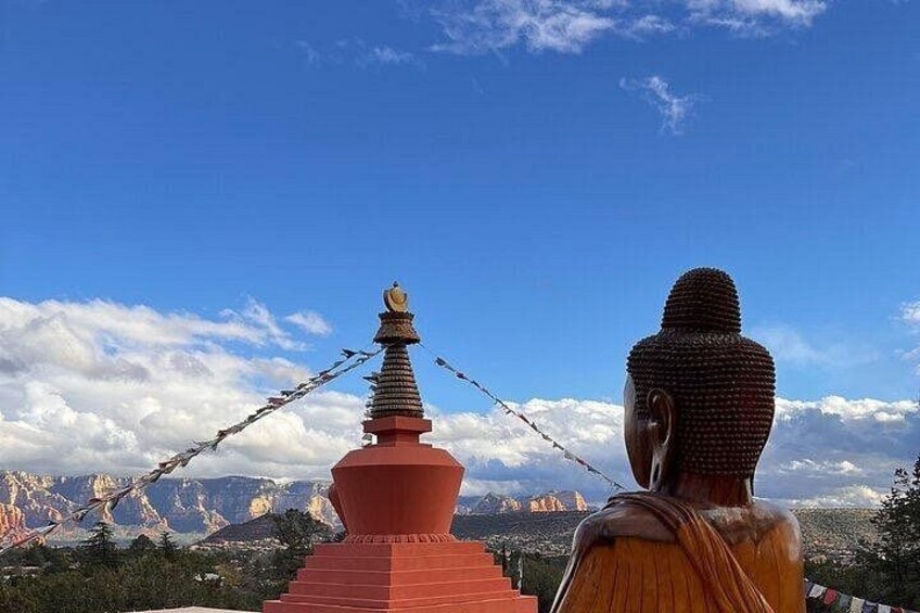 A large Buddha statue, a red stupa, and a mountainous landscape under a blue sky. 5