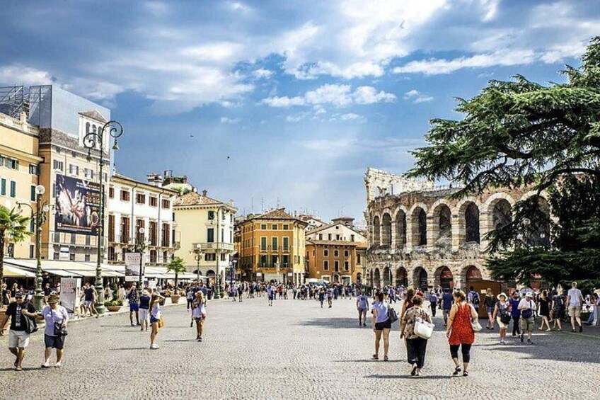 A bustling square with historic architecture, including a prominent building with arches. 3