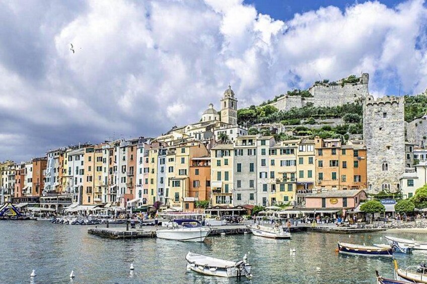 A coastal town with colorful buildings, a castle, and boats in the harbor. 5