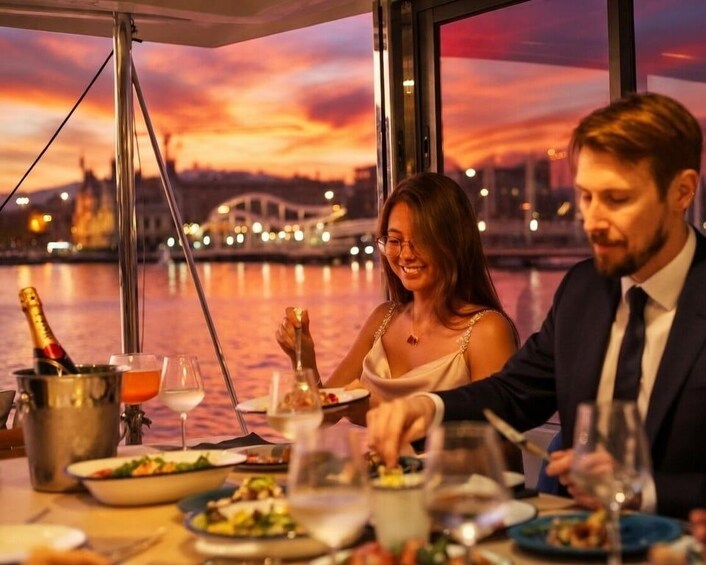 Una pareja cenando en una mesa con un paisaje urbano y un atardecer al fondo. 5