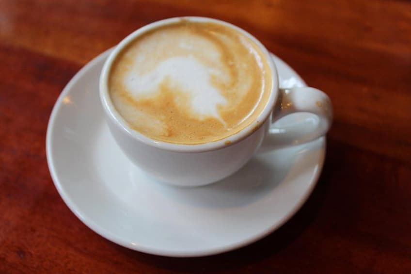 En kop kaffe med underkop på et træbord. 2