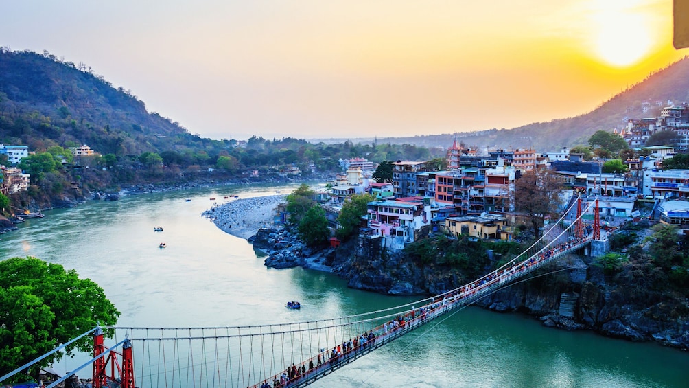 A suspension bridge over a river with buildings on the banks. 1