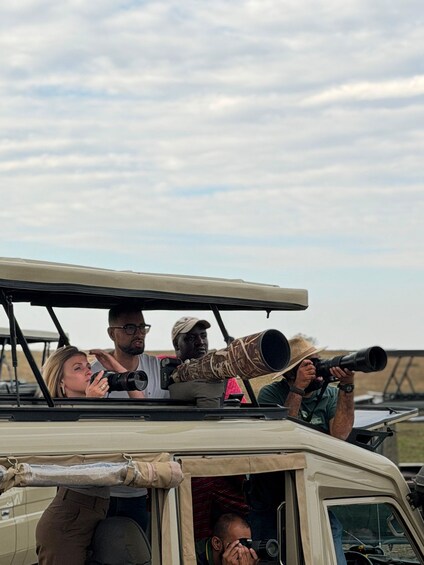 A group of people in a safari vehicle with mounted scopes. 1