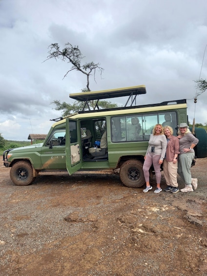 A green Land Cruiser parked on a gravel surface with a tree in the background. 1