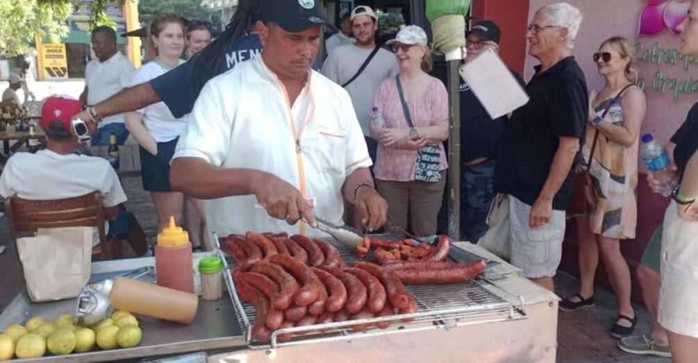 A street food vendor grilling sausages and preparing food at a market. 4