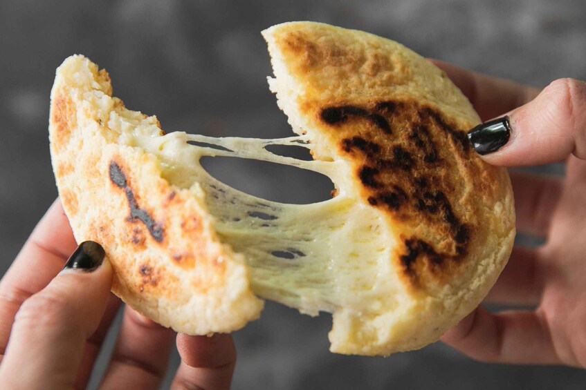 A person holding a piece of bread with a bite taken out, revealing a soft, airy interior. 1