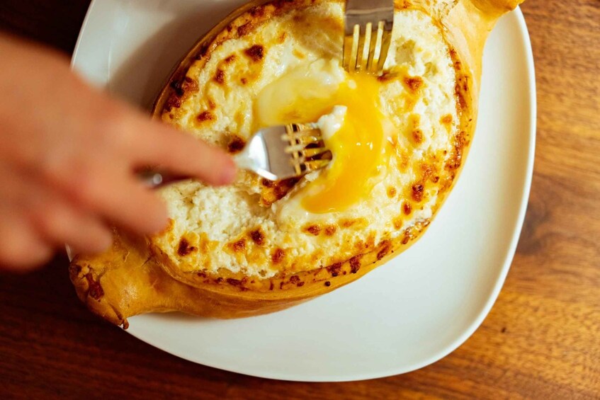 A toasted bread with a fried egg on top, being cut with a fork. 2