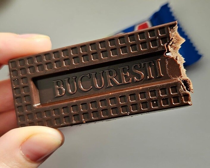 A hand holding a partially broken chocolate bar with the word 'BUCRESTI' visible. 2