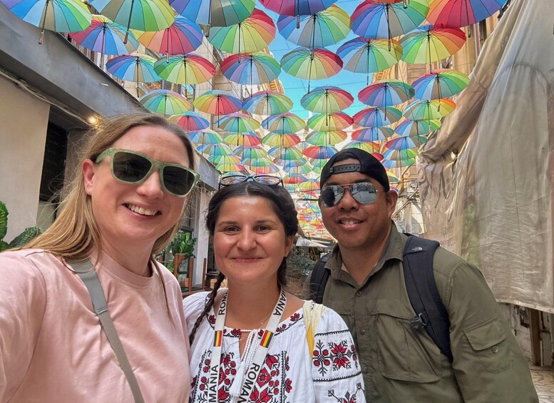 A street with colorful umbrellas overhead and people standing. 5