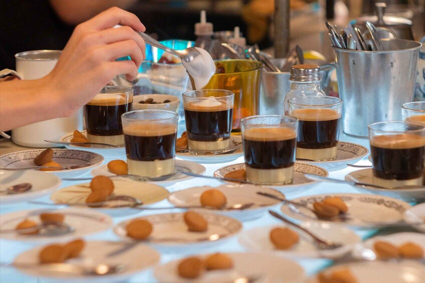 A table with multiple glasses of coffee and plates of almonds. 5