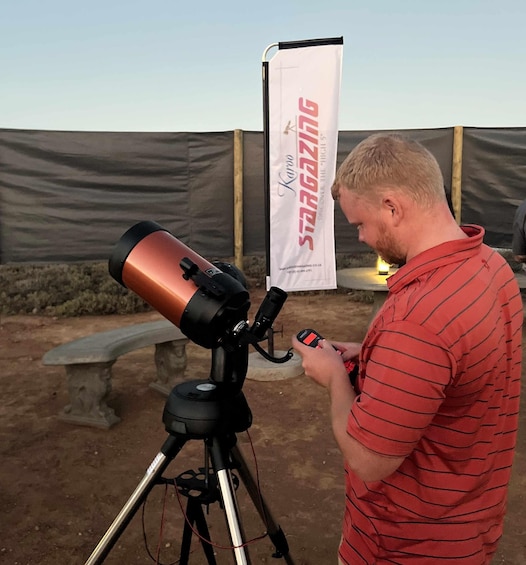 A person using a telescope on a tripod in an outdoor setting. 3