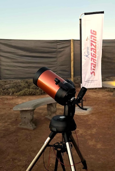 A telescope on a tripod in an outdoor setting with a banner in the background. 5