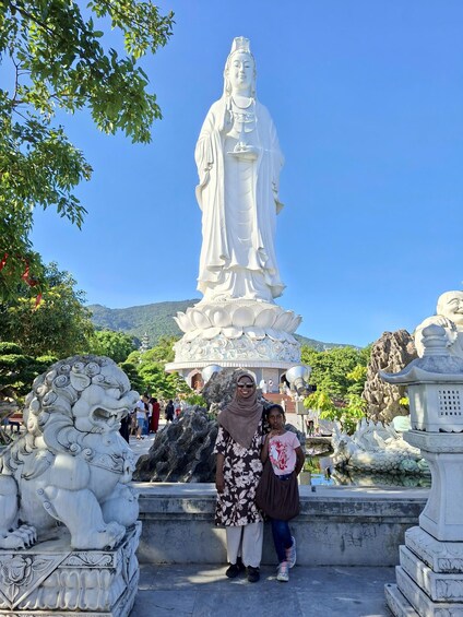 A large white statue of a robed figure, a stone lion, and a pagoda-like structure with a lotus base. 5