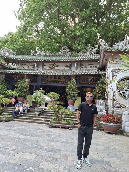 A traditional Chinese architectural structure with ornate roof tiles and detailed carvings, surrounded by potted plants and a stone pathway. 3