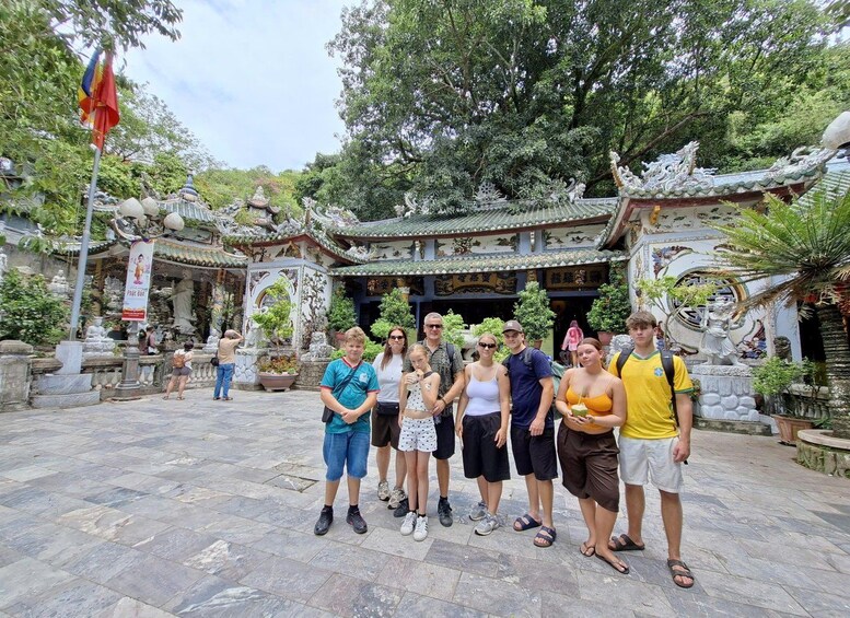 A group of people standing in front of a traditional Chinese gate with intricate designs and statues. 2