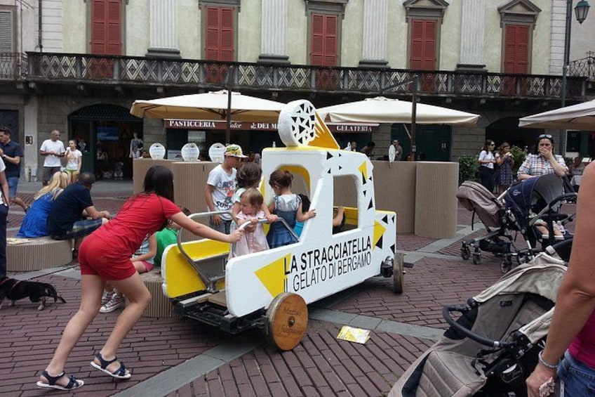 Un pequeño camión de helados amarillo y blanco con la leyenda 'LA STRACCIAETTA GELATO DI BERGAMO'. 3