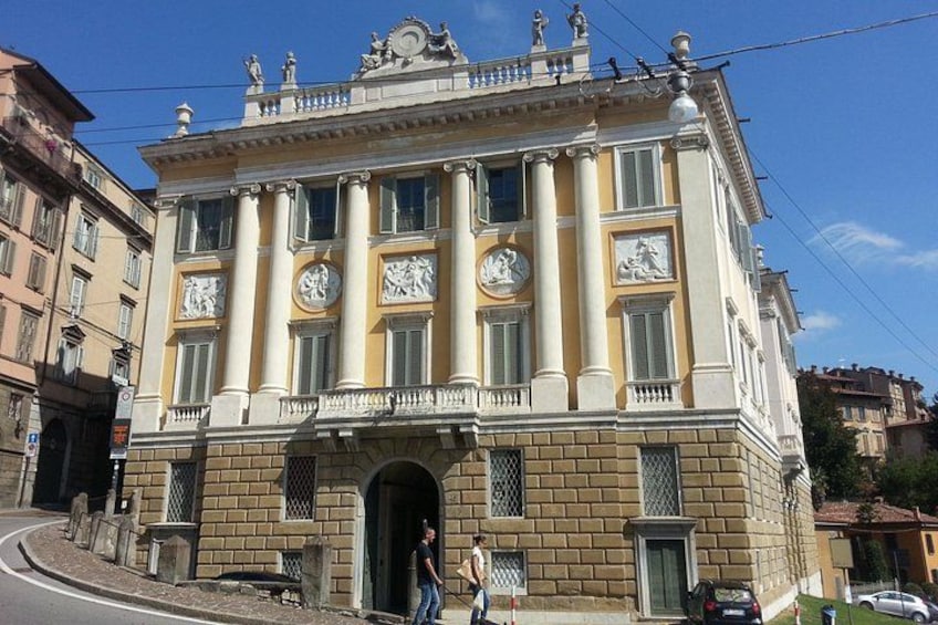Un edificio histórico con columnas, un balcón y un reloj. 4