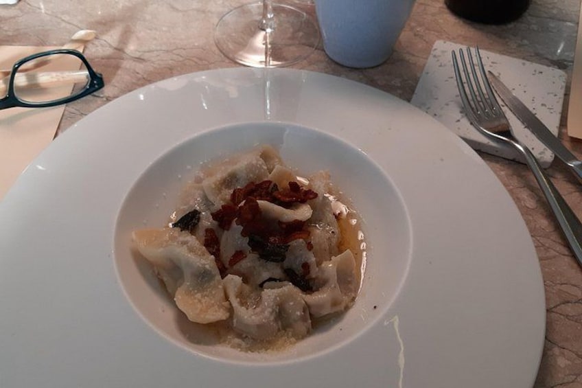Un plato de ravioles con salsa roja y decoración sobre una mesa de mármol. 2