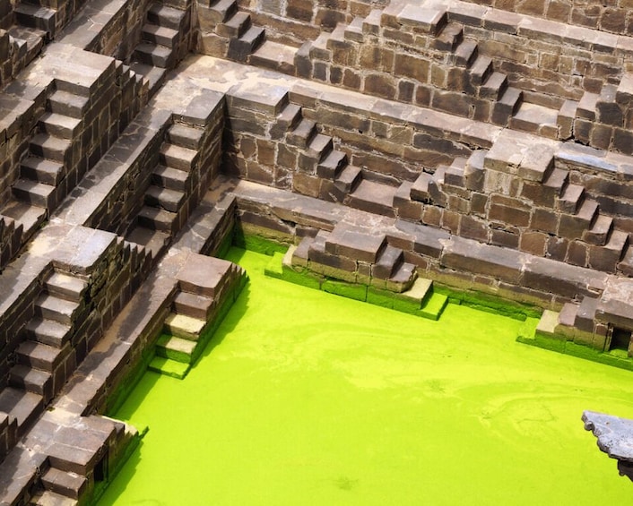 A stone structure with a green pool. 4