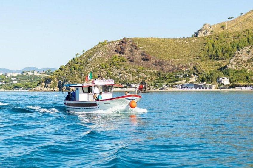 A boat with a red and white hull moving through a body of water, with a mountainous landscape in the background. 5