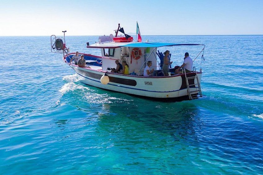 A boat with passengers on a clear blue sea. 3