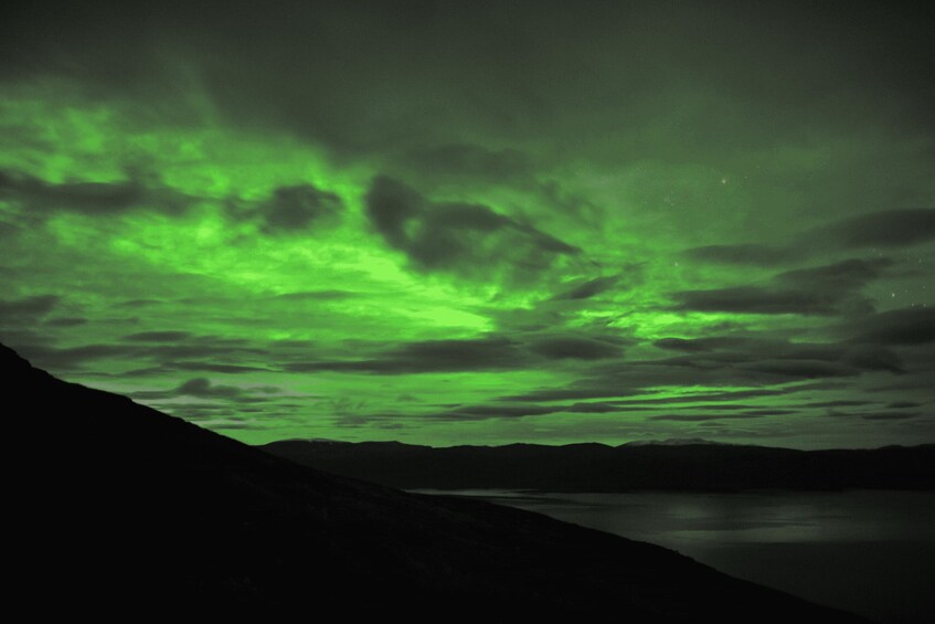 A night sky with green aurora borealis over a mountainous landscape and a lake. 2