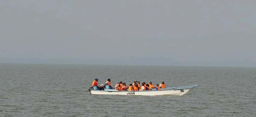 A boat with people wearing orange life jackets on calm water. 4