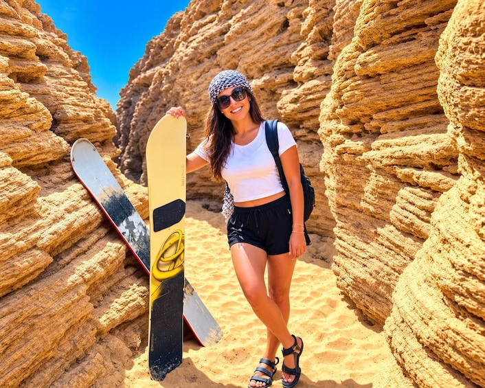 A person standing in a rocky canyon with a snowboard. 3