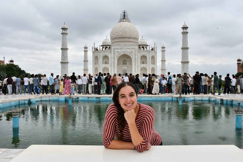 A person sitting by a pool with the Taj Mahal in the background. 2