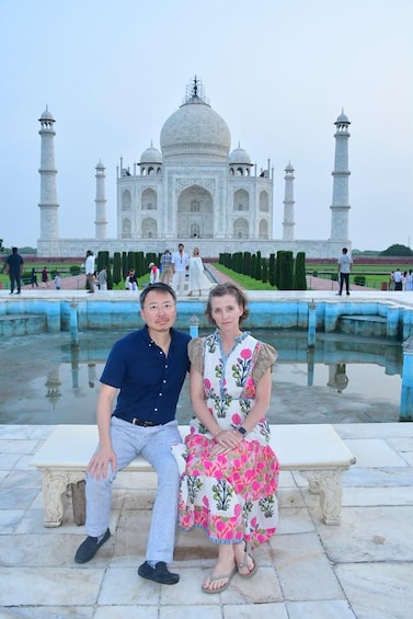 A couple sitting on a bench with the Taj Mahal in the background. 5