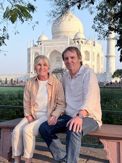 Two people sitting on a bench with the Taj Mahal in the background. 3