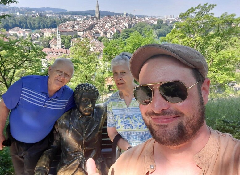 A group of people standing near a statue with a cityscape in the background. 4