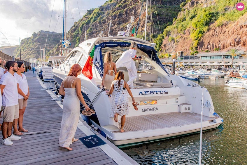 A white yacht named 'MADEIRA' docked at a marina with a rocky hillside in the background. 1