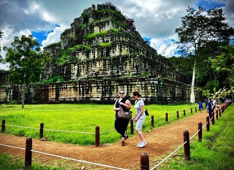 A large ancient stone structure surrounded by lush greenery and a pathway with visitors. 3