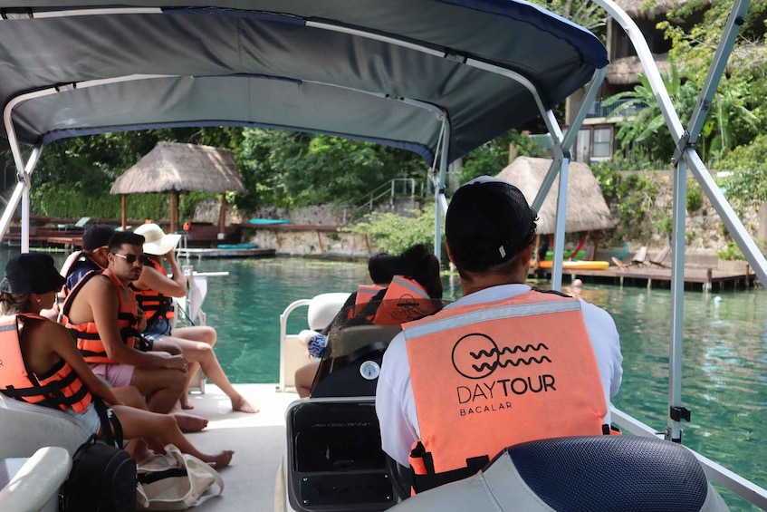 A boat tour with passengers wearing life jackets and a guide in an orange vest. 4