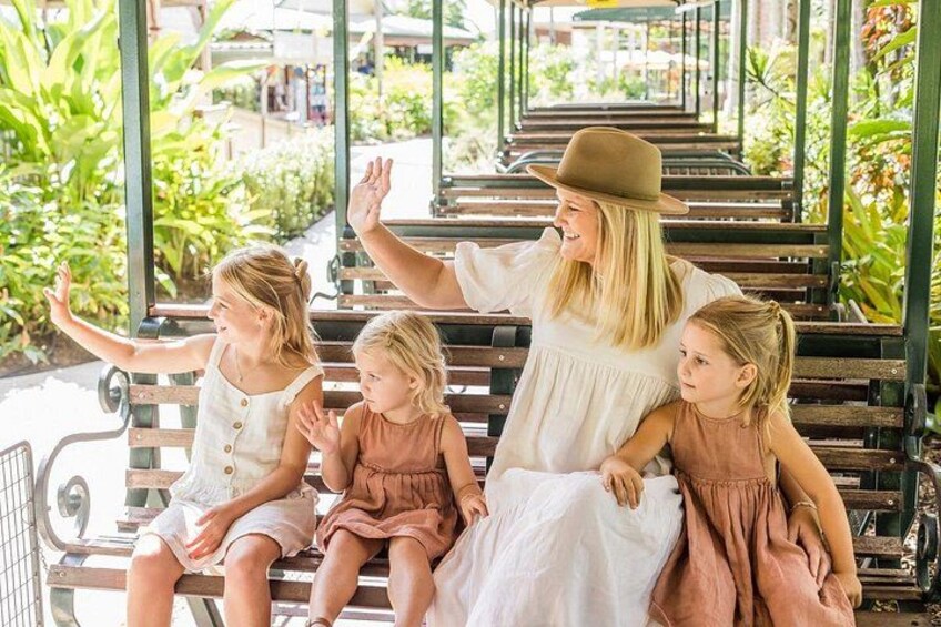 Une femme vêtue d’une robe blanche et d’un chapeau est assise sur un banc, accompagnée de trois enfants. 4