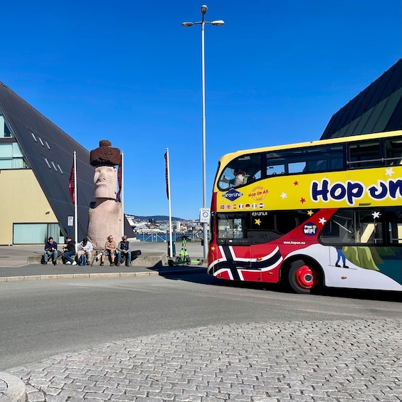 A double-decker bus with 'Hop On Hop Off' branding parked at a bus stop. 5